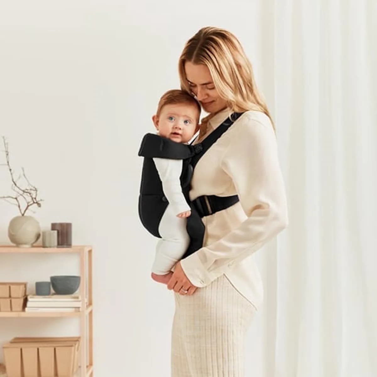 Parent wearing the BabyBjörn Mini with the baby facing inwards, side view